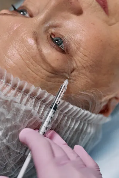 Senior woman receiving professional anti-aging facial injection